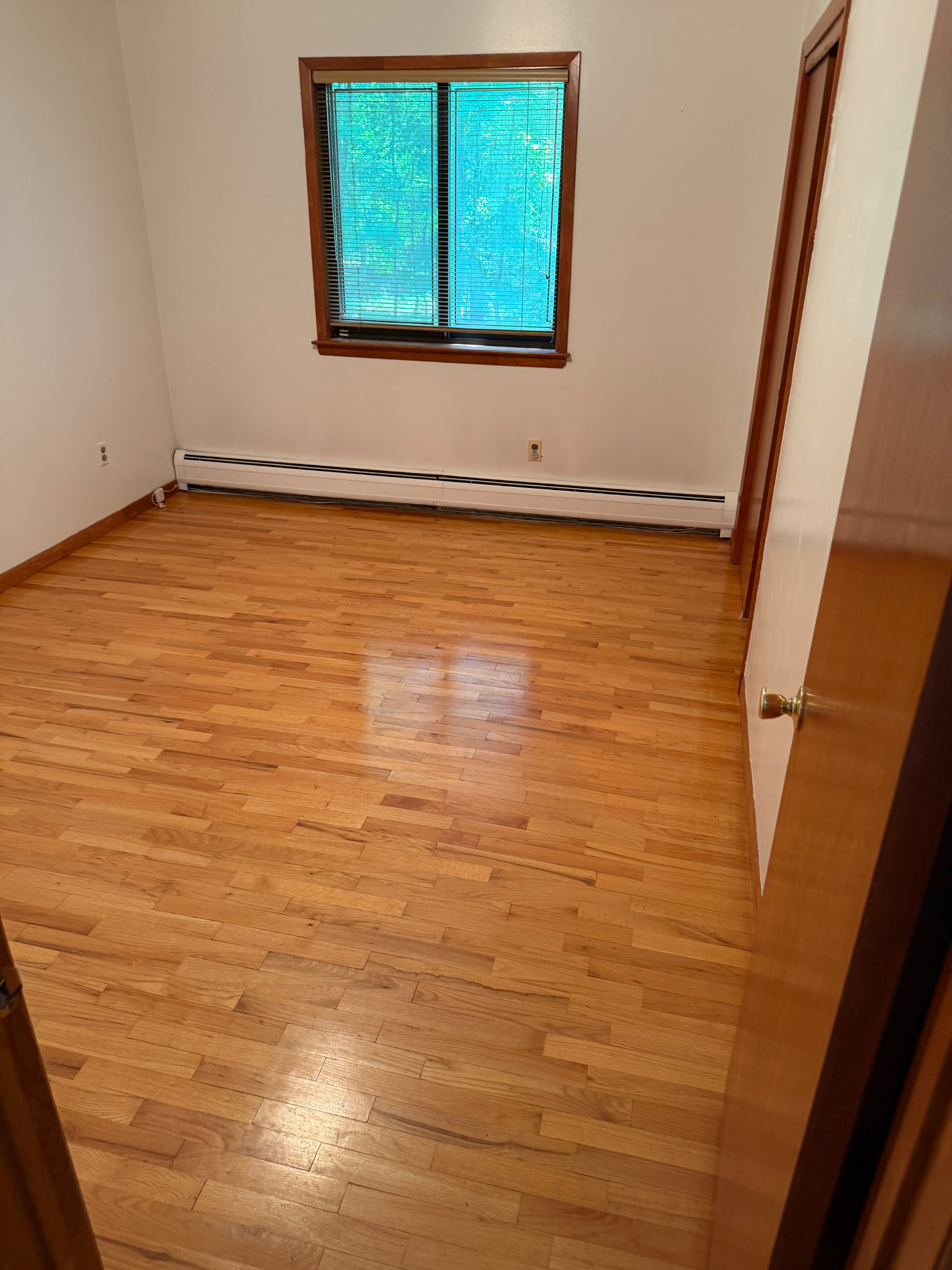 Polished hardwood bedroom floor and clean baseboards after a Clean & Shine visit