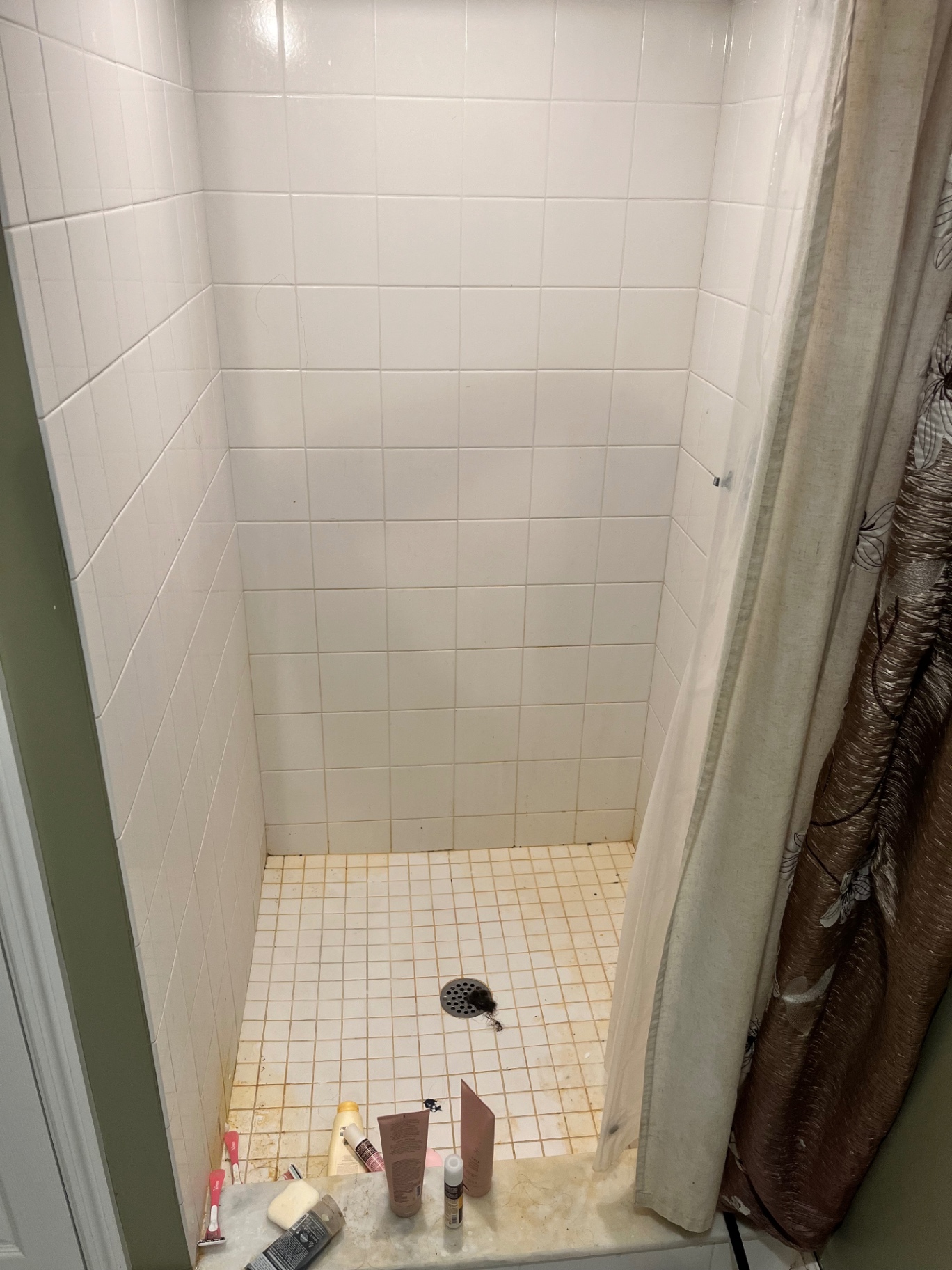 Shower stall with stained grout and soiled floor tile before a Clean & Shine visit