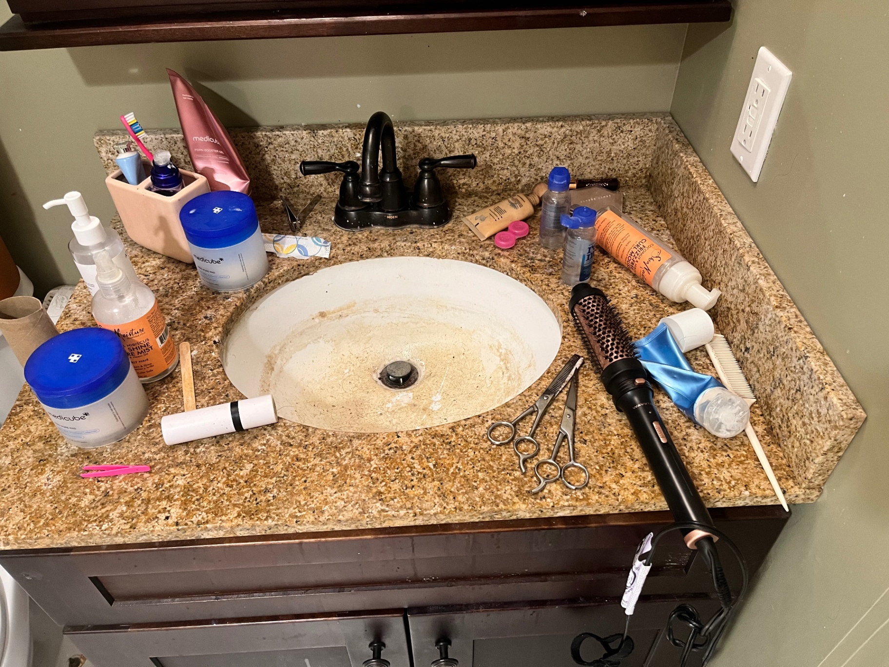 Crowded bathroom counter with products and tools before a Clean & Shine visit